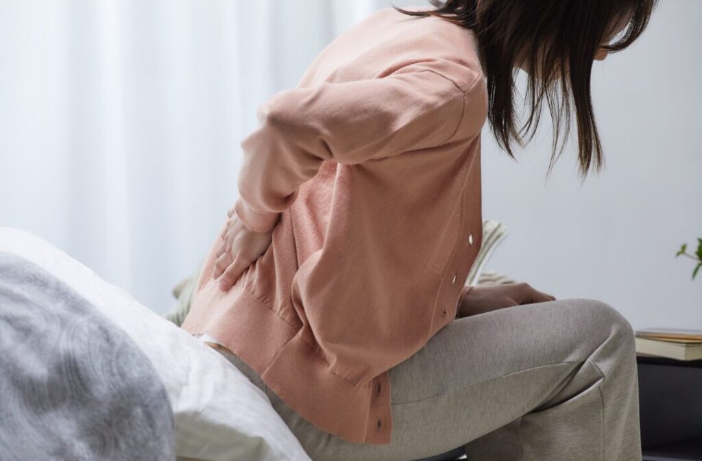 腰の痛みでつらそうな女性