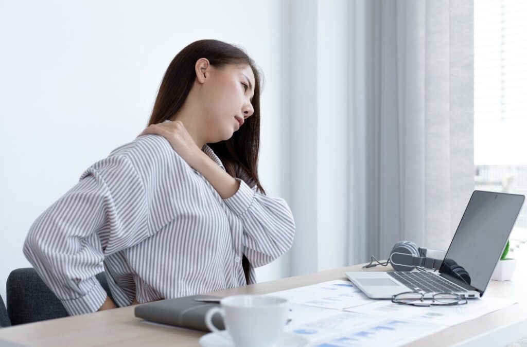 肩こりと首の痛みで仕事中しんどそうな女性